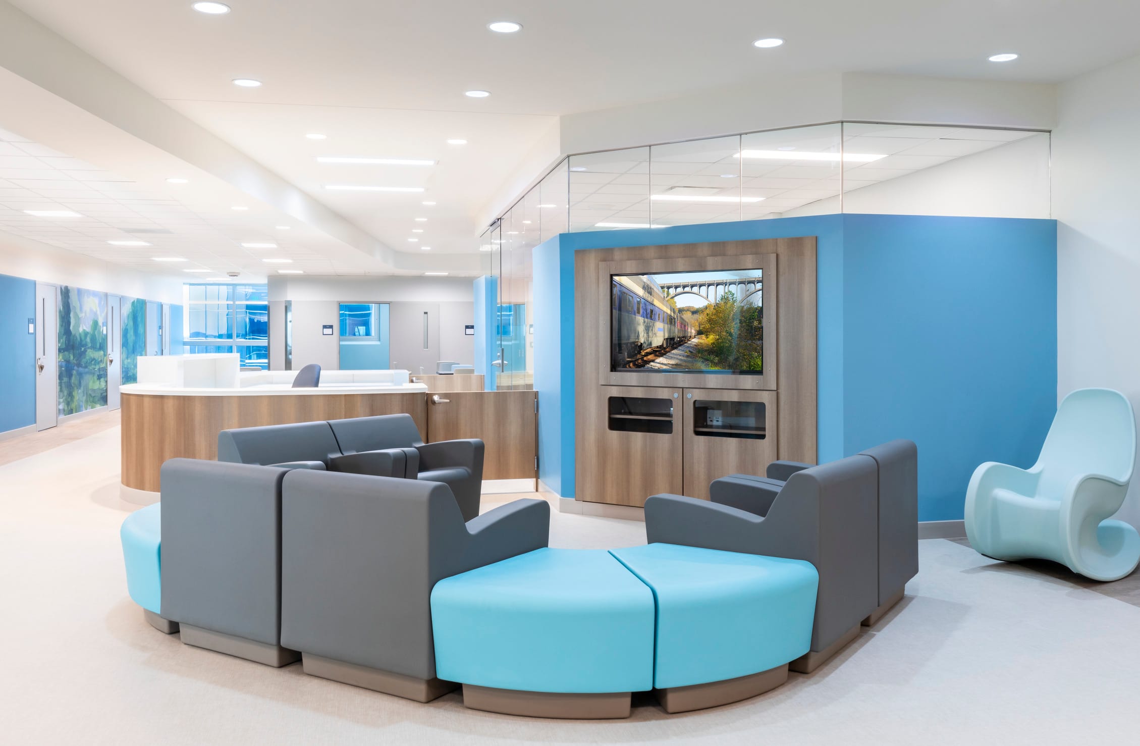 Interior of the NeuroDiagnostic Institute waiting room lobby. The walls and furniture are brightly colored shades of blue. The LED lighting creates a cheerful, airy environment. The interior is very light and not at all like the inside of a stereotypical psychiatric facility, highlighting BSA's expertise in environments that prioritize healing and patient well-being.