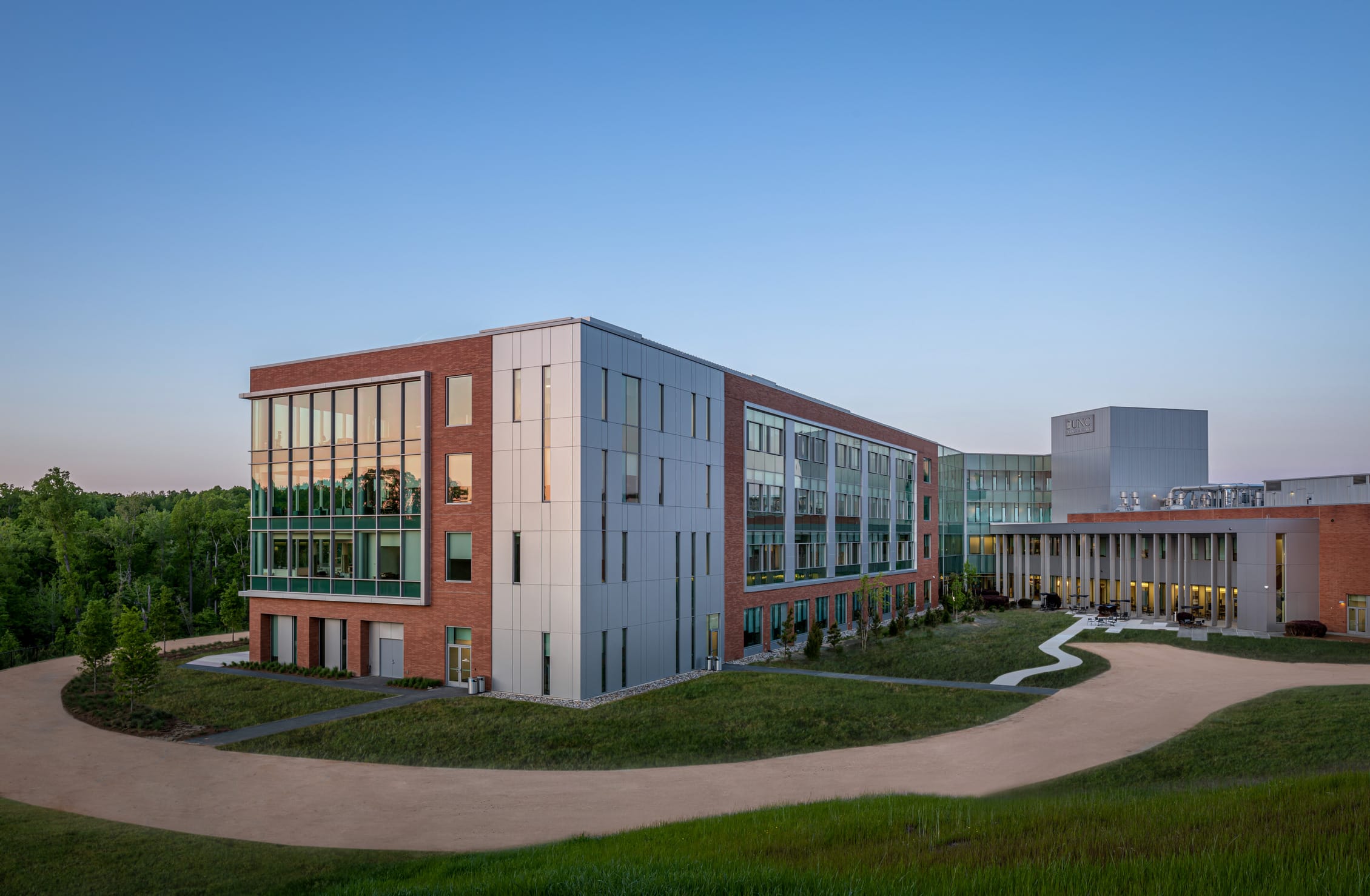 UNC Hospitals Hillsborough exterior featuring an all-glass design aside from brick pillars. This image showcases BSA's expertise in exterior architecture and blending different materials.