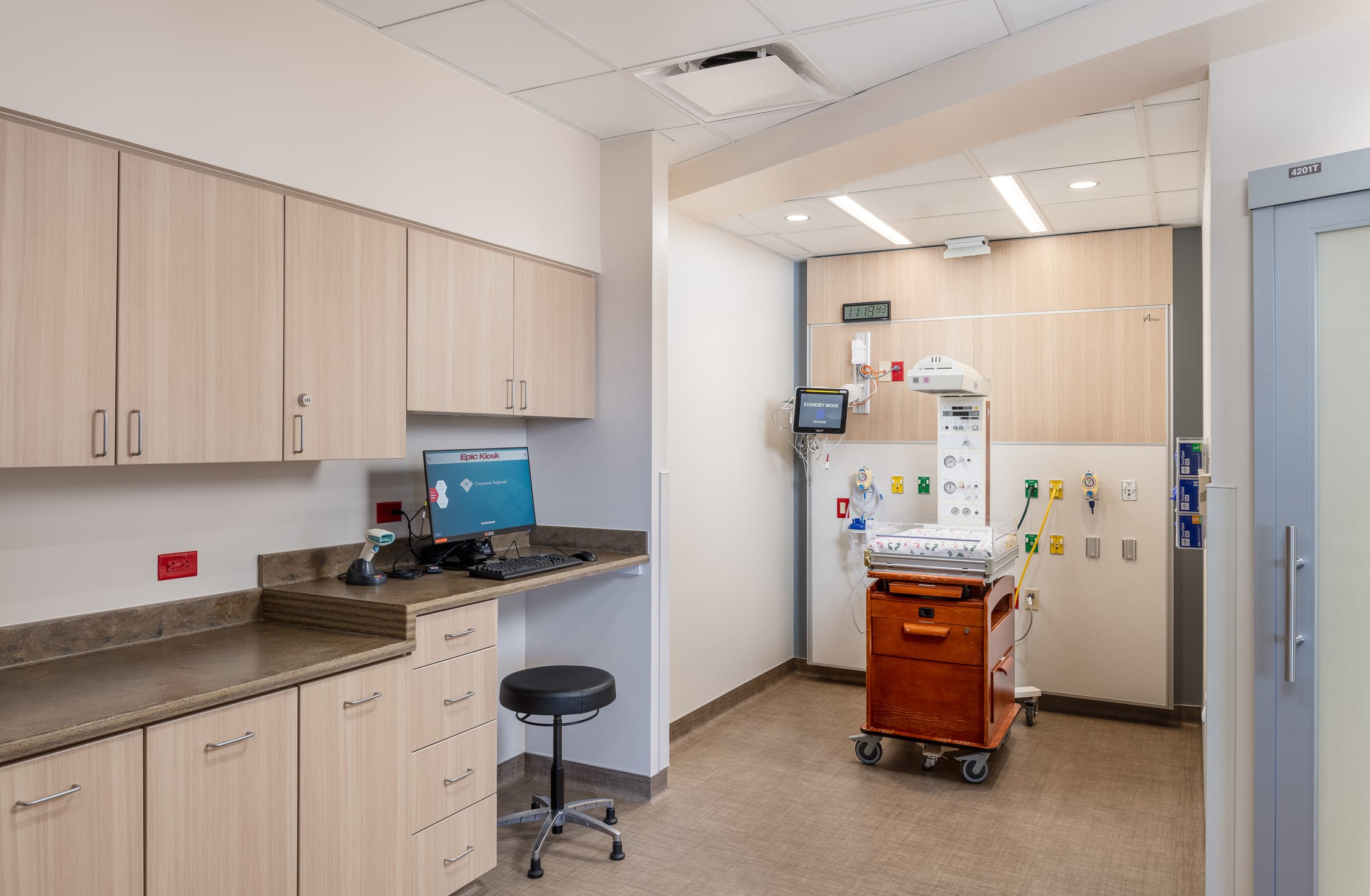 This image shows a clinical workspace in the Cheyenne Regional Medical Center's labor and delivery unit. On the left side is a staff workstation with a computer displaying an
